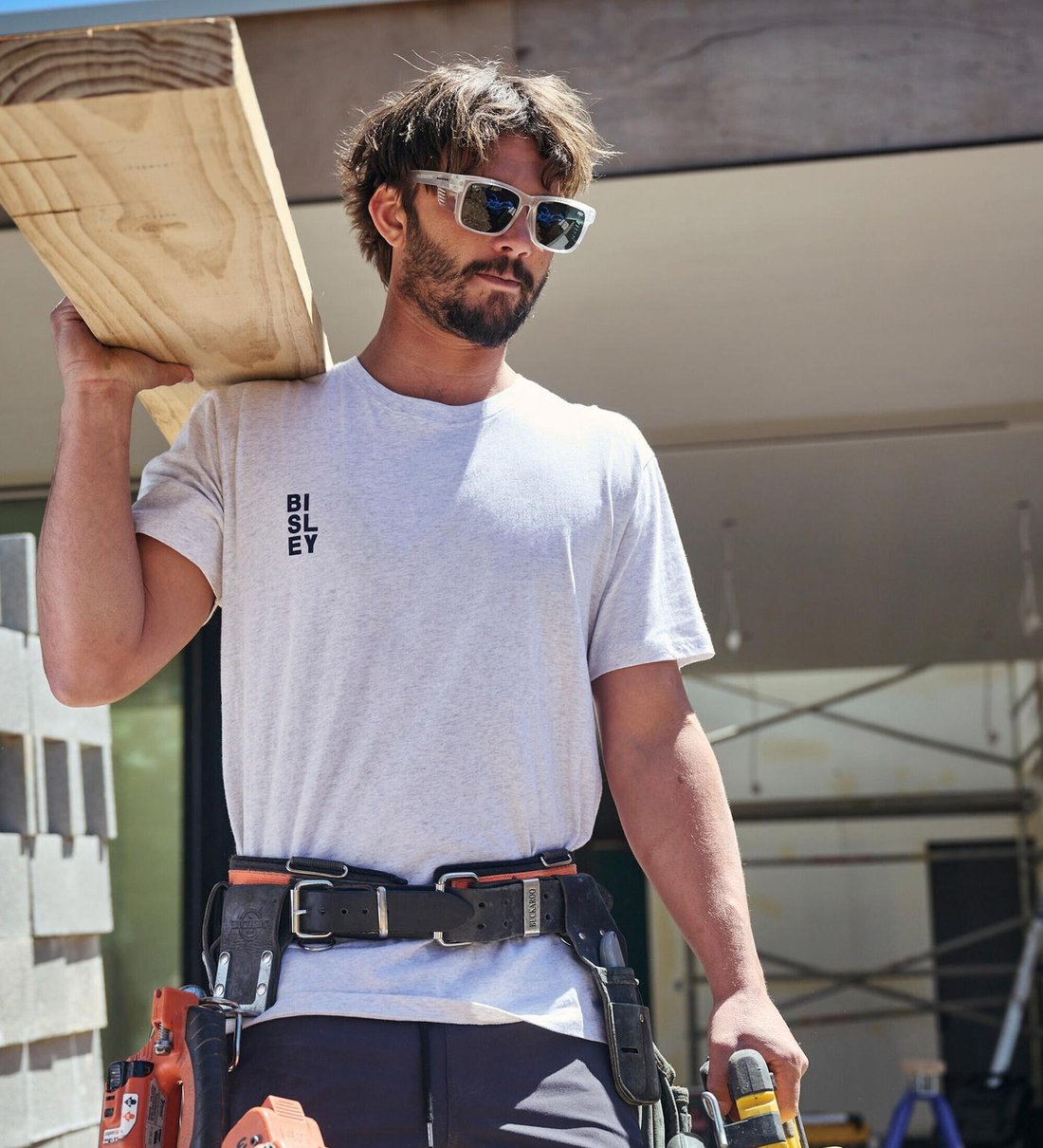 Tradie in a white Bisley tee carrying timber