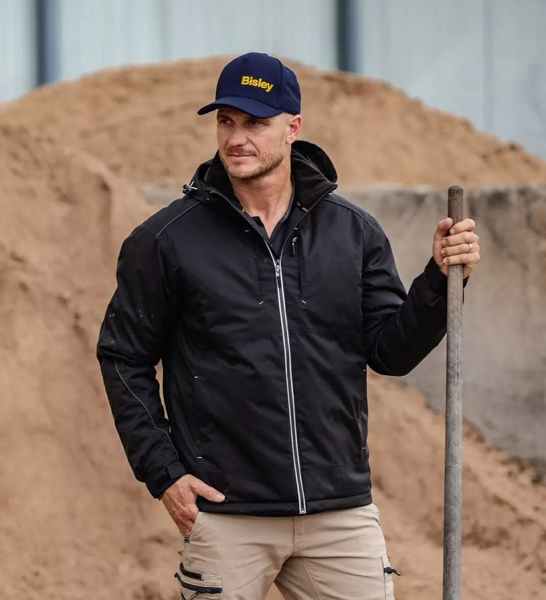 Worker in a black Bisley jacket and cap on site