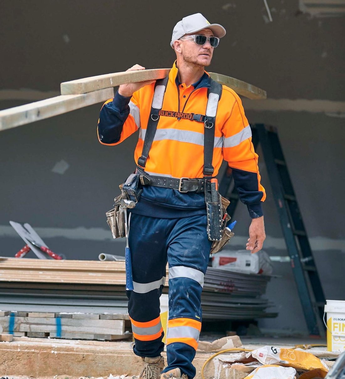 Tradie in a Bisley hi-vis shirt and taped pants carrying timber