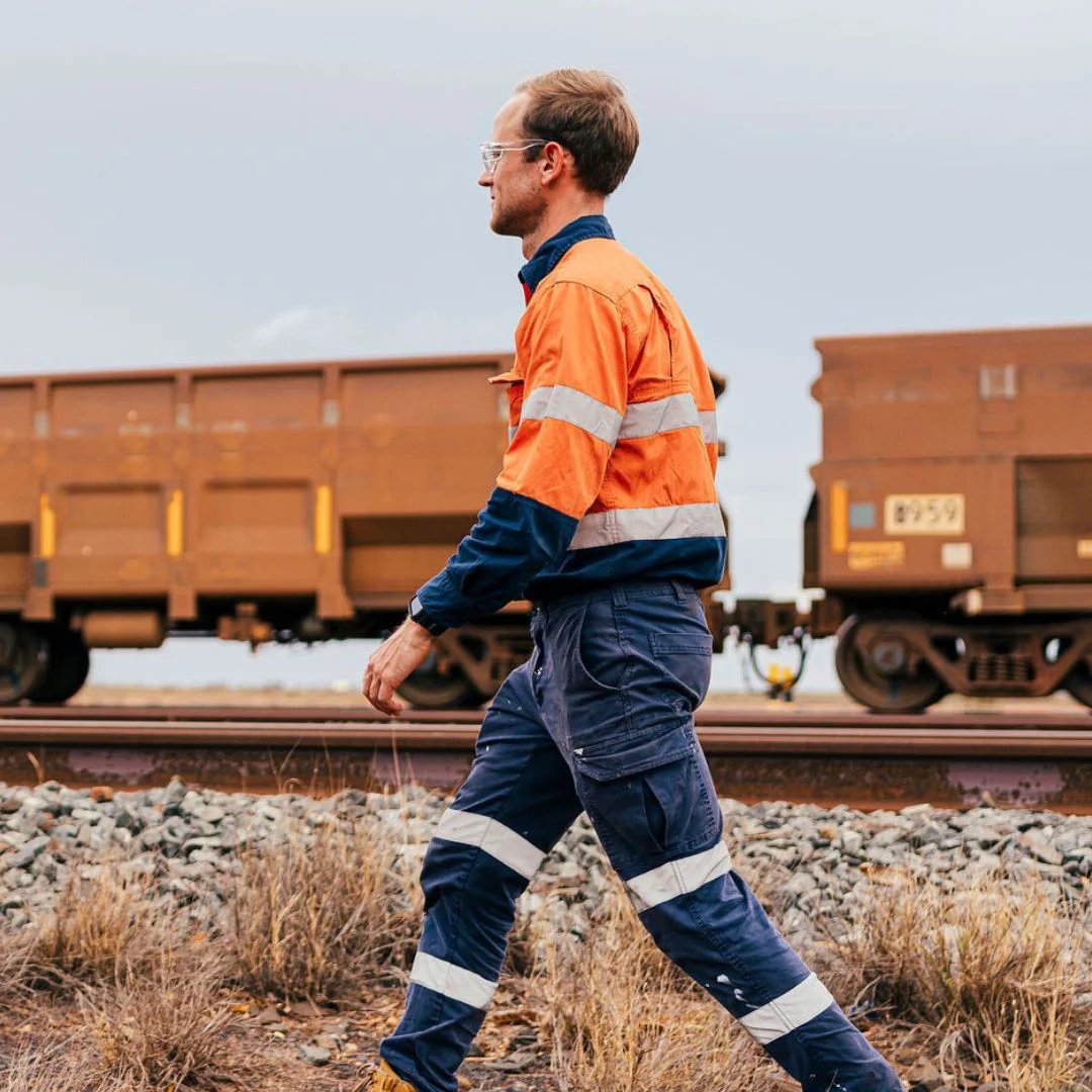 Mine worker in hi-vis and Steel Blue boots beside ore wagons