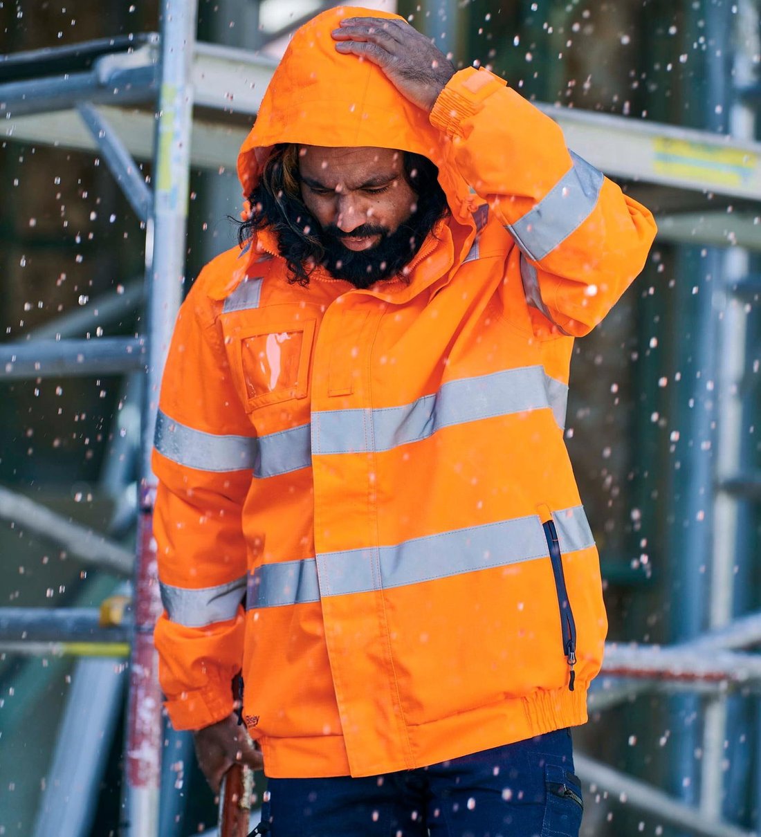 Worker in a Bisley taped hi-vis rain jacket with the hood up in the rain